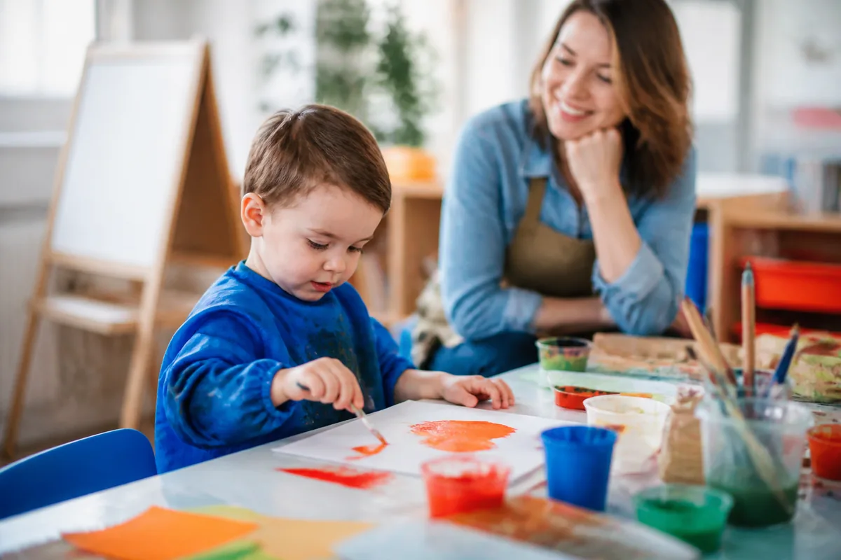 Enfant créatif réalisant une activité manuelle avec un adulte qui l'encourage