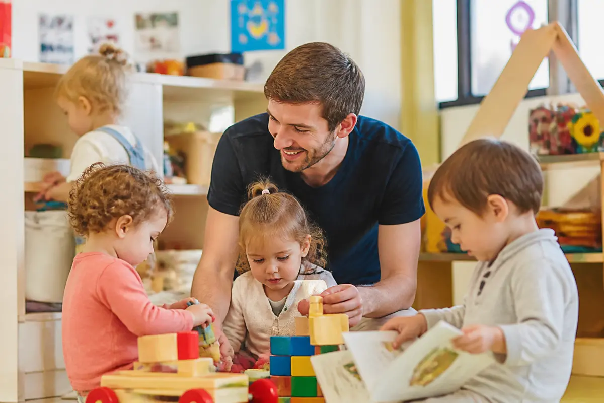 Éducateur formé aidant des jeunes enfants à jouer et apprendre ensemble en classe
