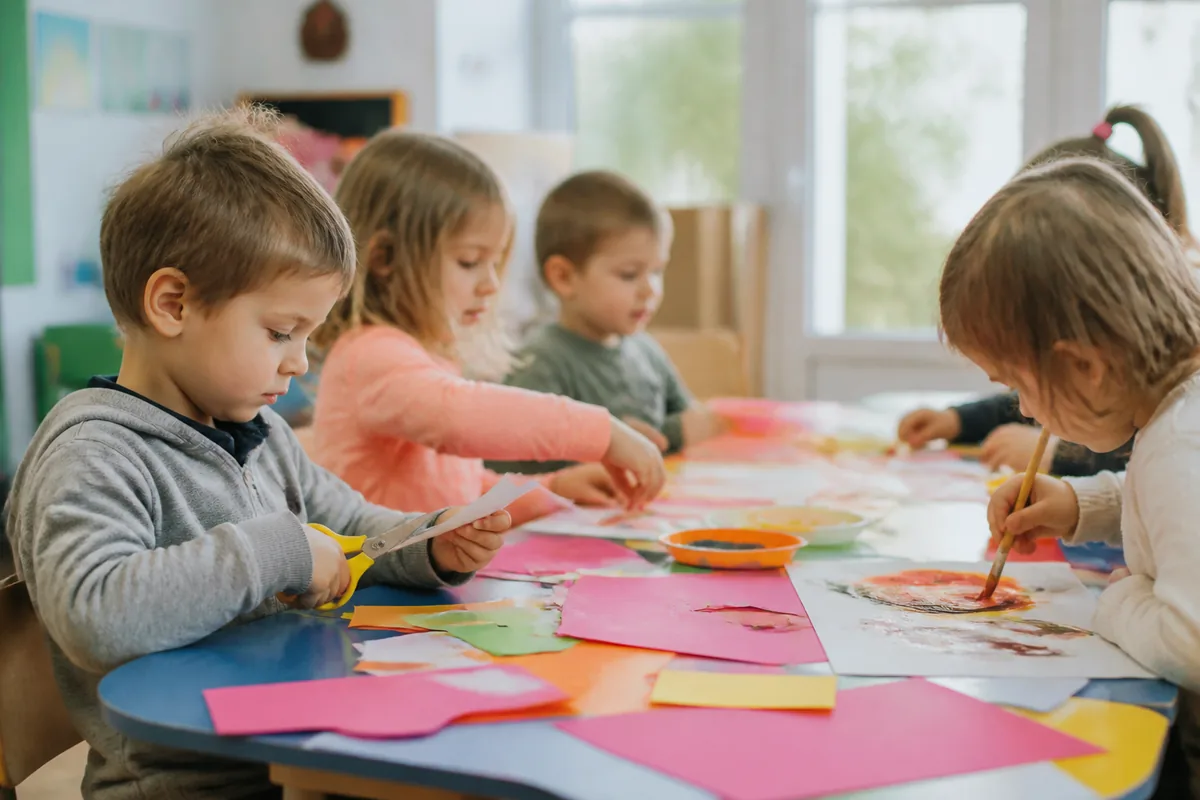 Enfants participant à des ateliers créatifs manuels avec peinture et découpage